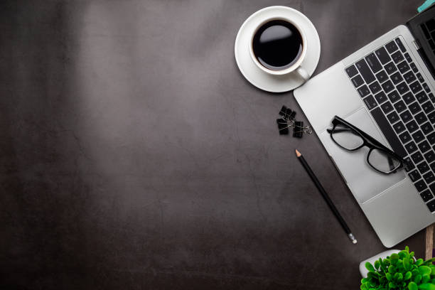 istock Top view desk,Modern office desk Workspace with laptop computer, coffee cup, glasses,notebook and office supplies for Working background concept. 1309888554