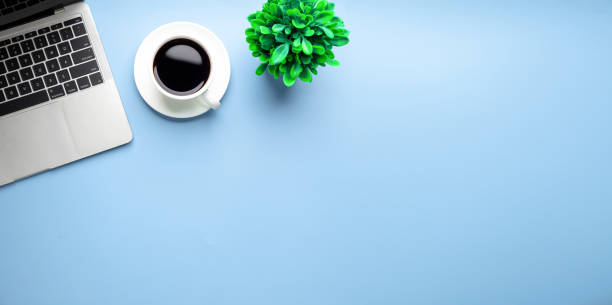 istock Flat lay, top view office table desk. Workspace with, laptop,office supplies, pencil, green leaf, and coffee cup on blue background. 1309888596