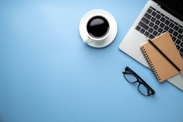 istock Flat lay, top view office table desk. Workspace with, laptop,office supplies, pencil, green leaf, and coffee cup on blue background. 1309888607