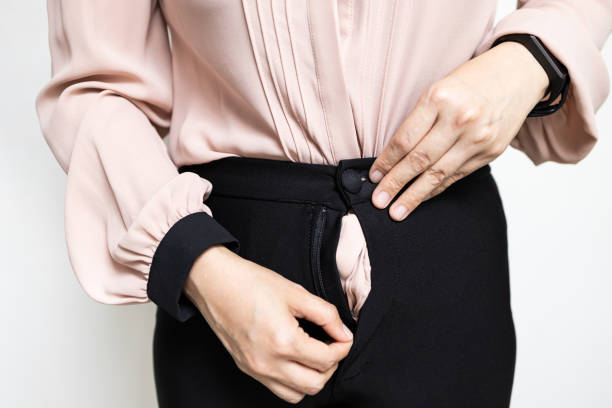 Hands of lady girl trying to zipping up her pants,try to close her tight pants with difficult from fat,weight gain,overweight or asian business woman having problem with zipper of trousers,bad quality manos de la chica señora tratando de engarrándose los pantalones, tratar de cerrar sus pantalones apretados con difícil de grasa, aumento de peso, sobrepeso o mujer de negocios asiática que tiene problemas con cremallera de pantalones, mala calidad