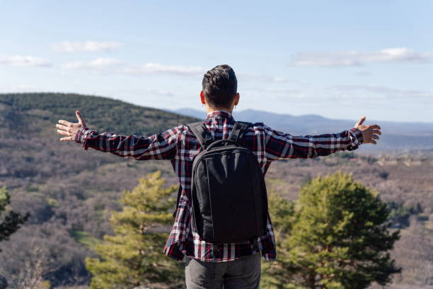 istock Man with backpack and open arms looking at the mountain 1309890189