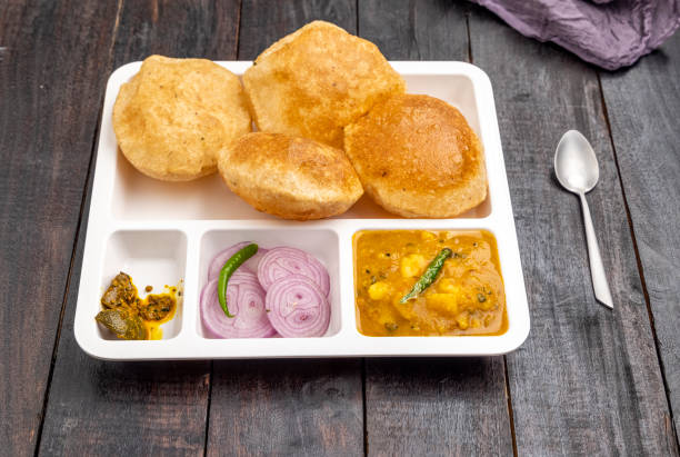 masala aloo sabzi ou curry de batata indiano servido com puri frito ou poori com cebola fatiada e picles de manga em um prato branco - 3409 - fotografias e filmes do acervo