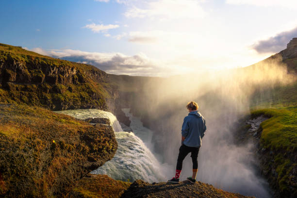 joven excursionista de pie en el borde de la cascada gullfoss en islandia - gullfoss falls fotografías e imágenes de stock