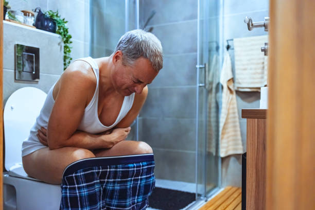 This alone time is essential for the body Photo of mature man on toilet is crouching forward in pain because of his stomach cramps. gastroenteritis stock pictures, royalty-free photos & images