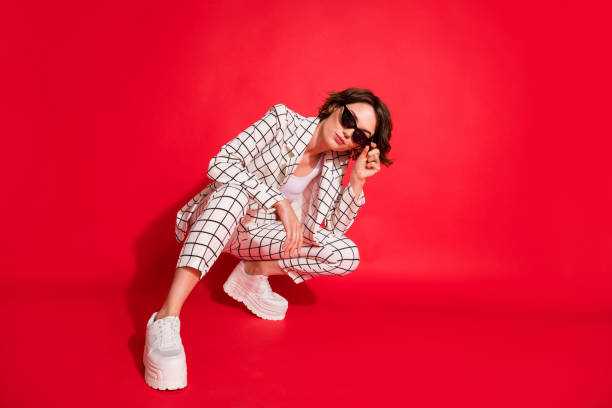 Full size photo of young attractive woman confident happy enjoy sit hand touch sunglass isolated over red color background Full size photo of young attractive woman confident happy enjoy sit hand touch sunglass isolated over red color background. fashion stock pictures, royalty-free photos & images