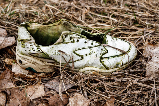 istock Old torn sneakers in dirty grass. 1309896568