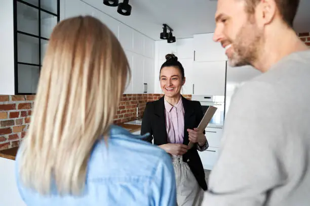 Photo of Happy real estate agent showing new apartment to a couple