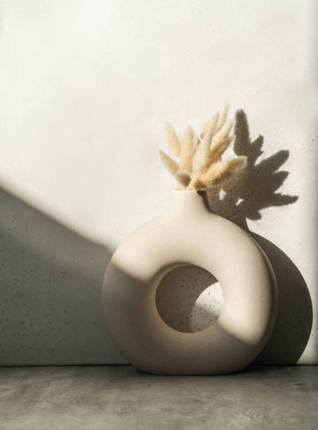 istock Round stylish ceramic vase with dried flower lagurus casting shadows 1309898123