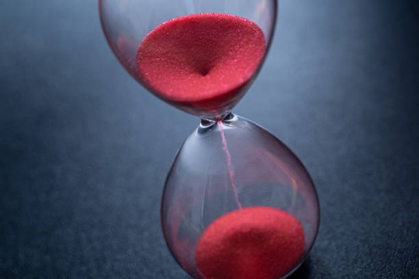 istock Sand passes through hourglass bulbs measuring the transit time counting down to the deadline, against a dark background 1309898129