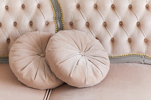 Two beige round pillows on a pastel fabric sofa background