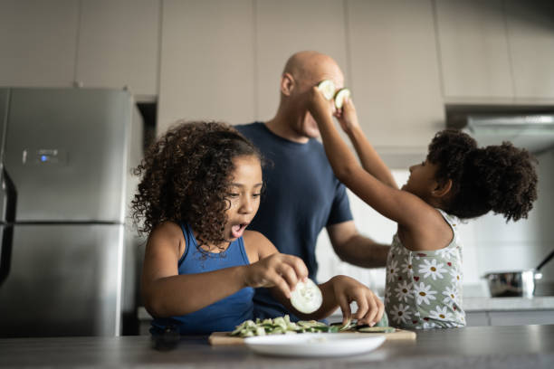 istock Father and daughters playing in the kitchen with cucumber slices 1309902538