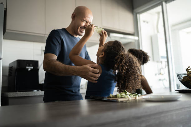 istock Father and daughters playing in the kitchen with cucumber slices 1309902571