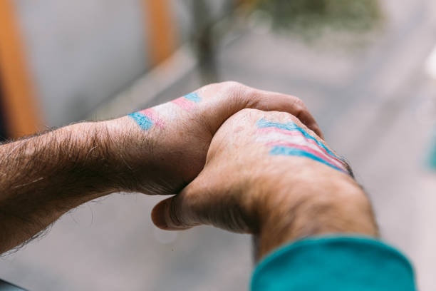 Transsexual man rests his hands with the transsexual flag painted on them, on a railing stock photo