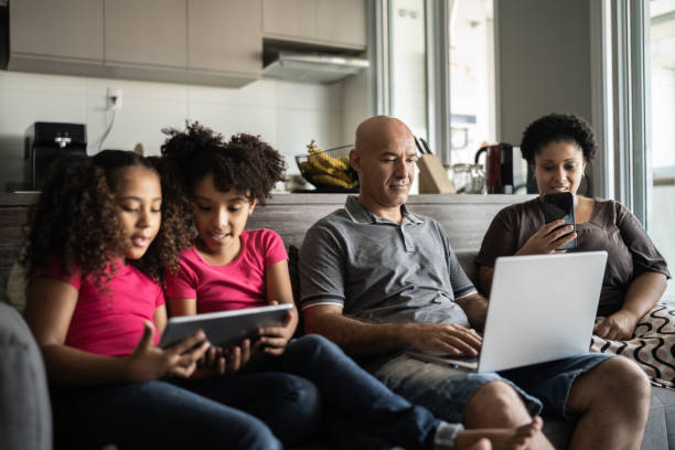 Family reunited in the living room using electronic devices Family reunited in the living room using electronic devices family dependency mother family with two children stock pictures, royalty-free photos & images