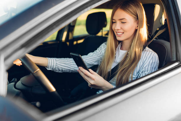 istock Young beautiful woman using mobile phone while driving in car 1309908963