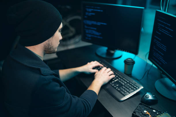 istock Hacker wearing a sweatshirt and cap tries to hack a security system to steal or destroy critical information or a ransom of important information of the company 1309909166