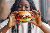 African woman with afro hair eating a tasty classic burger with fries.