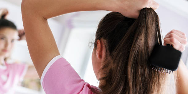 istock young brunette brushes hair in ponytail at mirror back view 1309912132