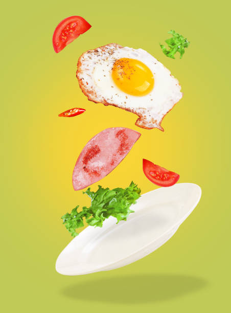 istock Scrambled eggs levitation with tomatoes, salad and sausage on green background 1309912690
