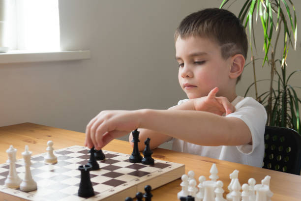 istock A preschool boy arranges pieces on a chessboard for playing chess. Board games. 1309913884