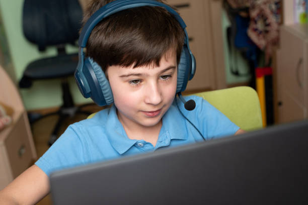 istock Smiling boy using laptop at home. On-line or e-learning education on quarantine. Soft focus 1309917248