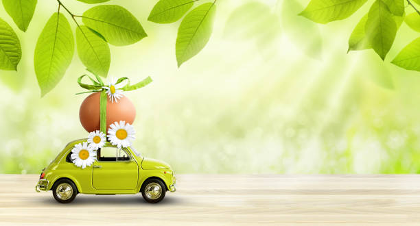 istock Retro car carrying an easter egg on the roof on fresh green spring foliage background. 1309917868