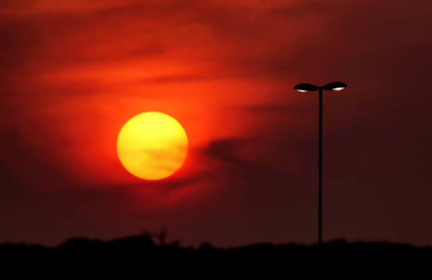 Big sun on the colorful evening sky and street lightning