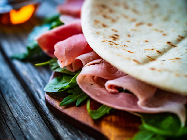 istock Italian piadina wraps - piada stuffed with prosciutto ham, spinach and arugula young leaves on wooden table 1309918901