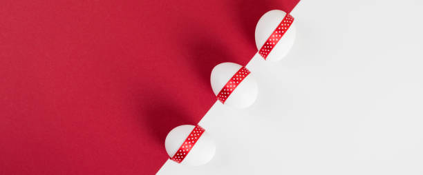 istock Easter banner. White Easter eggs decorated with red ribbon on red and white paper background. 1309922784