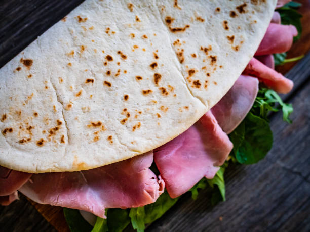 istock Italian piadina wraps - piada stuffed with prosciutto ham, spinach and arugula young leaves on wooden table 1309922847