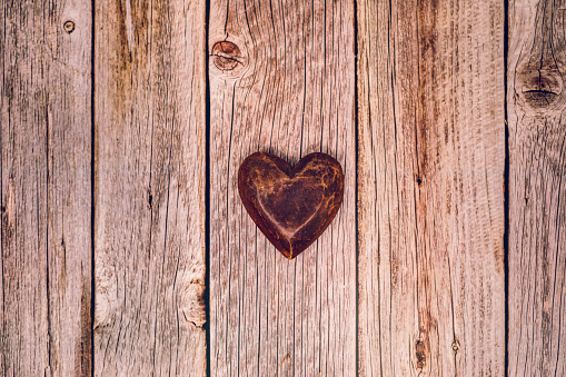 Brown wooden heart on brown vintage wooden background with copy space.  Added grain.