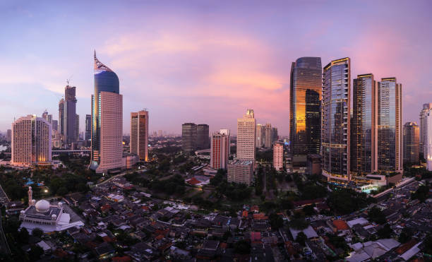 Stunning sunset over Jakarta skyline where modern office and condominium towers contrasts with traditional village, called Kampung, in Indonesia capital city Stunning sunset over Jakarta skyline where modern office and condominium towers contrasts with traditional village, called Kampung, in Indonesia capital city jakarta skyline stock pictures, royalty-free photos & images