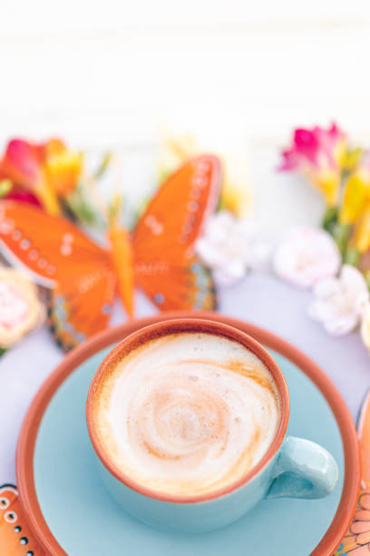 istock Bright blue cup with creamy coffee in boho style with spring flowers and butterfly 1309924285