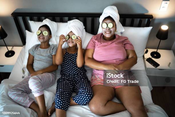 Morther And Daughters In Bed Doing Skin Care With Cucumber Slices Over The Eyes Stock Photo - Download Image Now