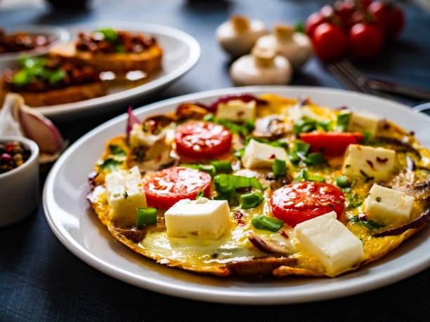 istock Continental breakfast -  scrambled eggs with feta cheese and fresh vegetables on wooden table 1309926433