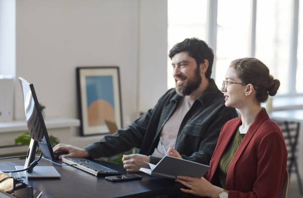 istock Two Smiling Business People at Workplace in Office 1309928228