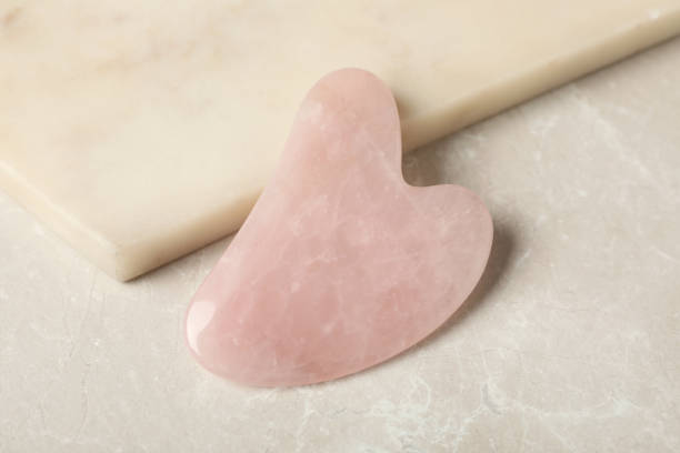 herramienta de cuarzo rosa gua sha cerca de la tabla en la mesa gris, primer plano - spooning fotografías e imágenes de stock