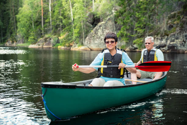 feliz pareja madura en chalecos salvavidas piragüismo en el lago del bosque - finland lake summer couple fotografías e imágenes de stock