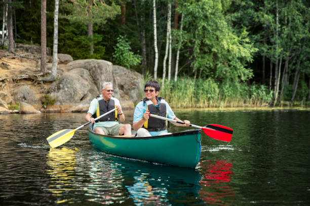 feliz pareja madura en chalecos salvavidas piragüismo en el lago del bosque - finland lake summer couple fotografías e imágenes de stock