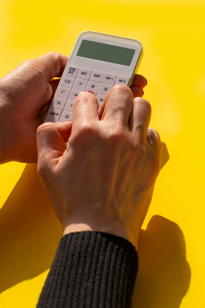 istock a white calculator in a woman's hand on a yellow background 1309933095