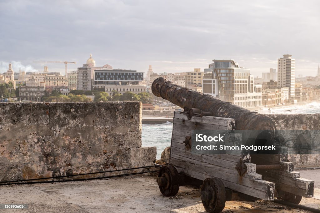 Old Rusty Cannon Against Havana Skyline Buildings In Cuba At Sunny Day. Close up Shot Old Rusty Cannon Against Havana Skyline Buildings In Cuba At Sunny Day. Cannon - Artillery Stock Photo