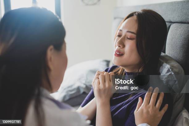 Female Doctor Giving Consoling To A Stressed Exhausted Upset Female Patient Suffering From Womens Sickness And Emotional Stress In Bedroom Stock Photo - Download Image Now