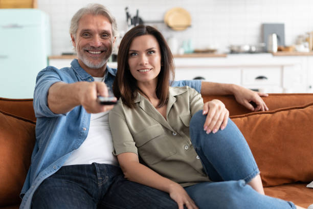 couples heureux regardant un film à la tv se reposant sur un divan à la maison. - friends television show photos et images de collection