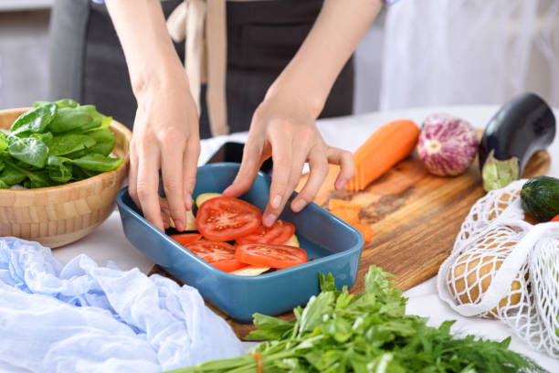 istock process of cooking vegetables with hands, tomatoes placed in baking dish, vegetarian dinner 1309940608