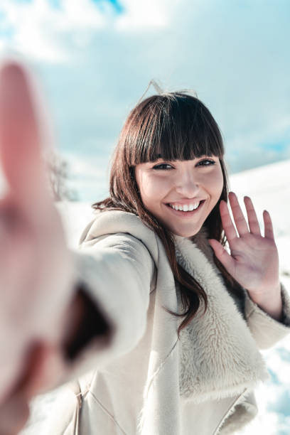 istock Cute Female Taking Smiling Selfie On Mountain In Snow 1309941726