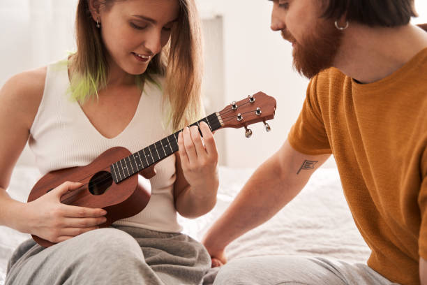 istock Tender young man helping to his girlfriend with playing at the ukulele 1309945060