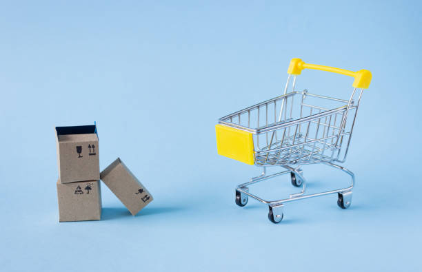 istock A small shopping trolley and boxes on a blue background. Shopping concept, side view. 1309946415