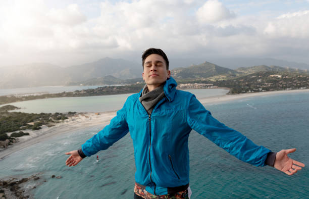 istock Man on a cliff with open arms enjoy the sea breeze and wind 1309946483