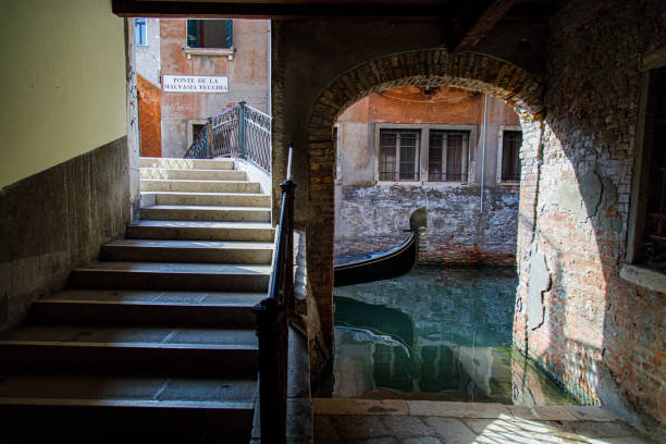 Gondola going underneath bridge, seen through archway, Venice, Italy