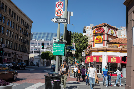 March 2021, Los Angeles California, USA- Los Angeles Downtown city view, with People wearing protective face masks due to COVID-19, crossing the street, and a view of El Pollo Loco restaurant